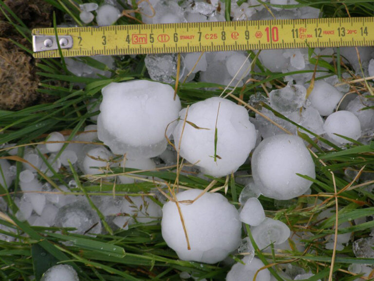 Hailstones roughly 4 cm across next to a tape measure, large enough to dent a car's hood or roof