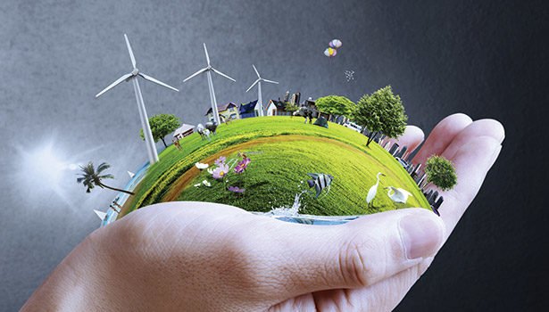Hand holding a small green globe with wind turbines and trees